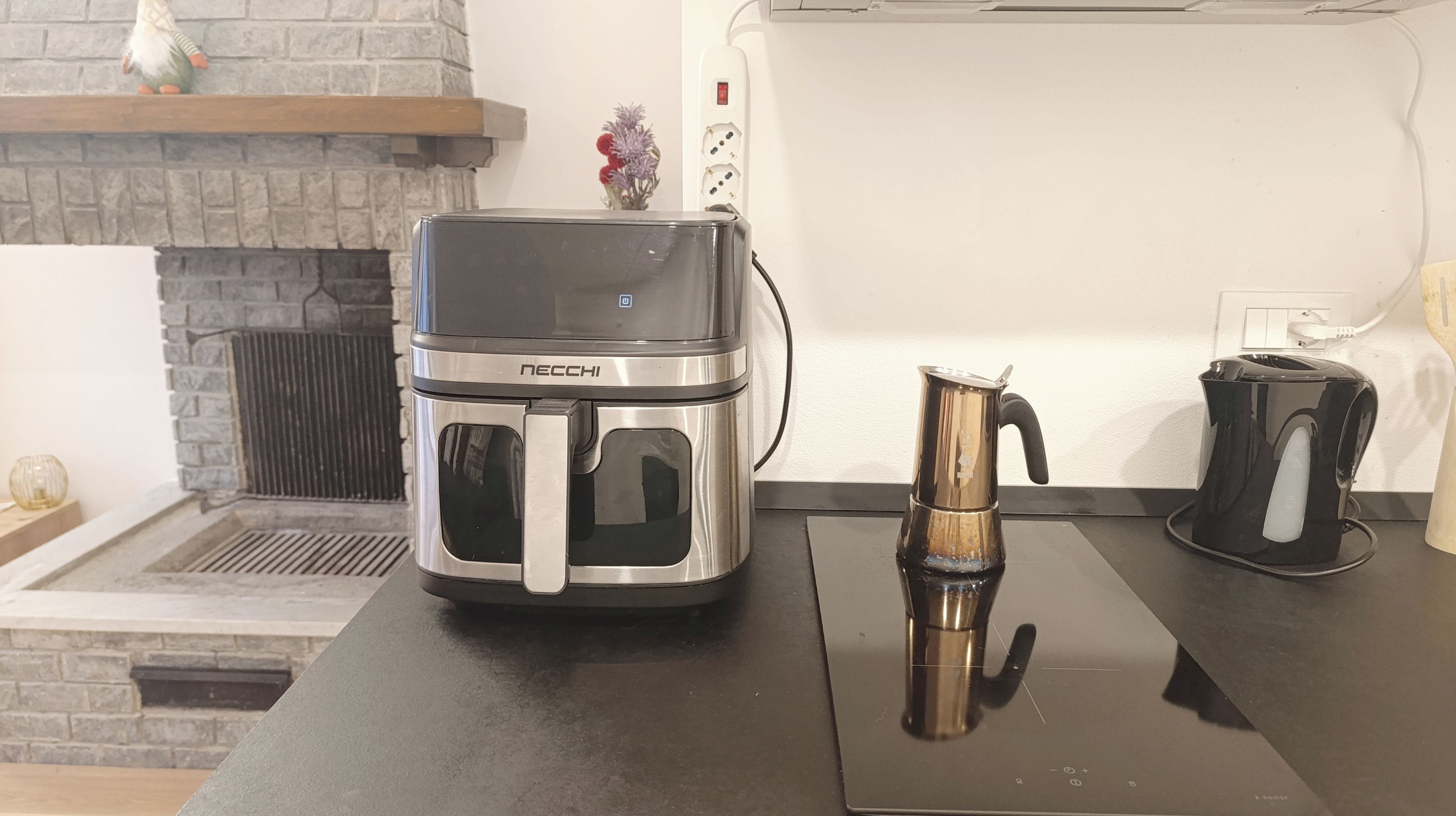 Una cocina con una cafetera moderna, un hervidor y una tostadora sobre la encimera.