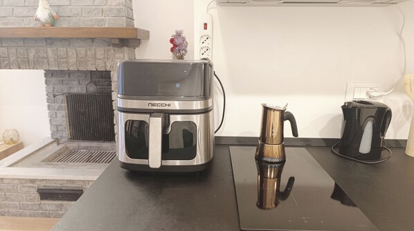 Una cocina con una cafetera moderna, un hervidor y una tostadora sobre la encimera.