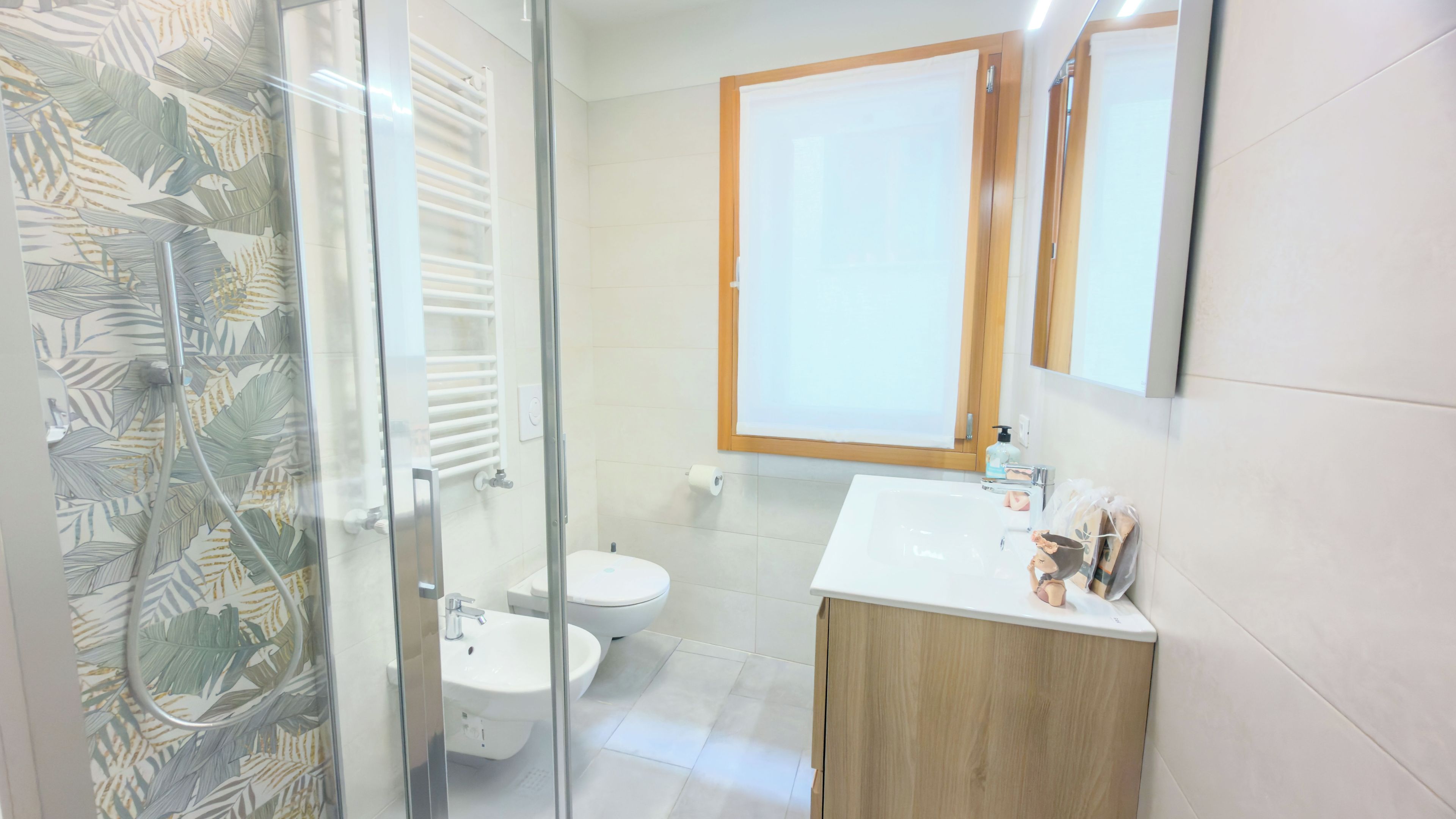 A bathroom with a glass shower enclosure, a toilet, a sink, and a mirror.
