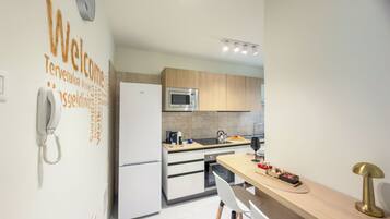 A modern kitchen with a refrigerator, microwave, and wooden cabinets.