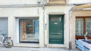 A building with a green door, a bicycle parked outside, and a window with a reflection. - Velvet Suite by Ca-sa Check (Chioggia)