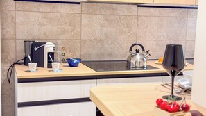 A kitchen with a coffee machine, kettle, and a wine glass on the counter. - Velvet Suite by Ca-sa Check (Chioggia)