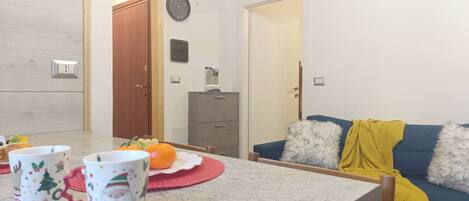 A living room with a sofa, a table with a fruit bowl, and a cabinet.