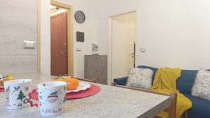 Ein Wohnzimmer mit einer Couch, einem Tisch mit Obstschale und einem Schrank.