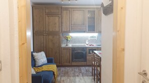 A compact kitchen with wooden cabinets, a built-in oven, and a dining area with a table and chairs.
