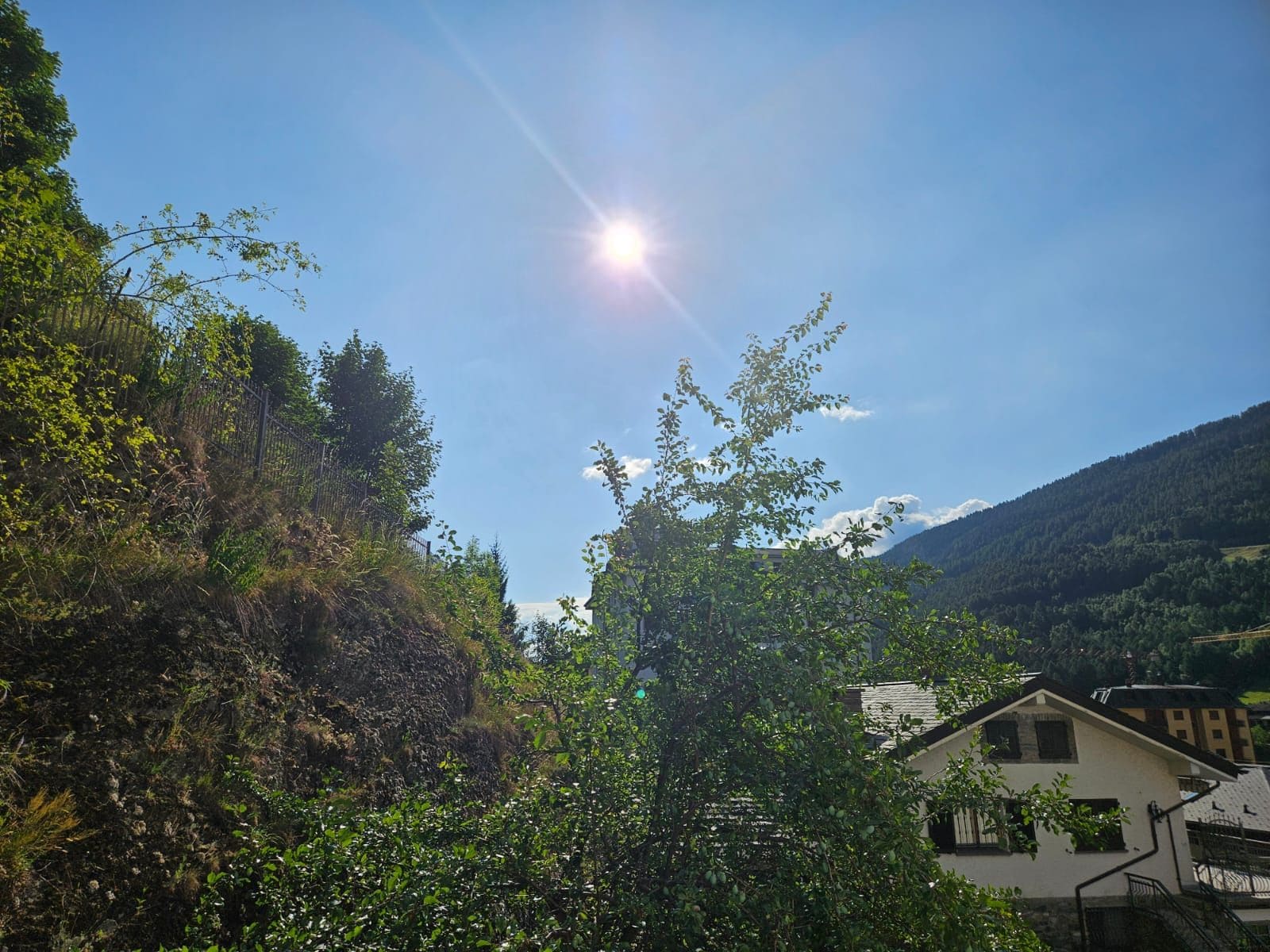 Paesaggio rurale con una casa circondata dal verde e dolci colline sullo sfondo.
