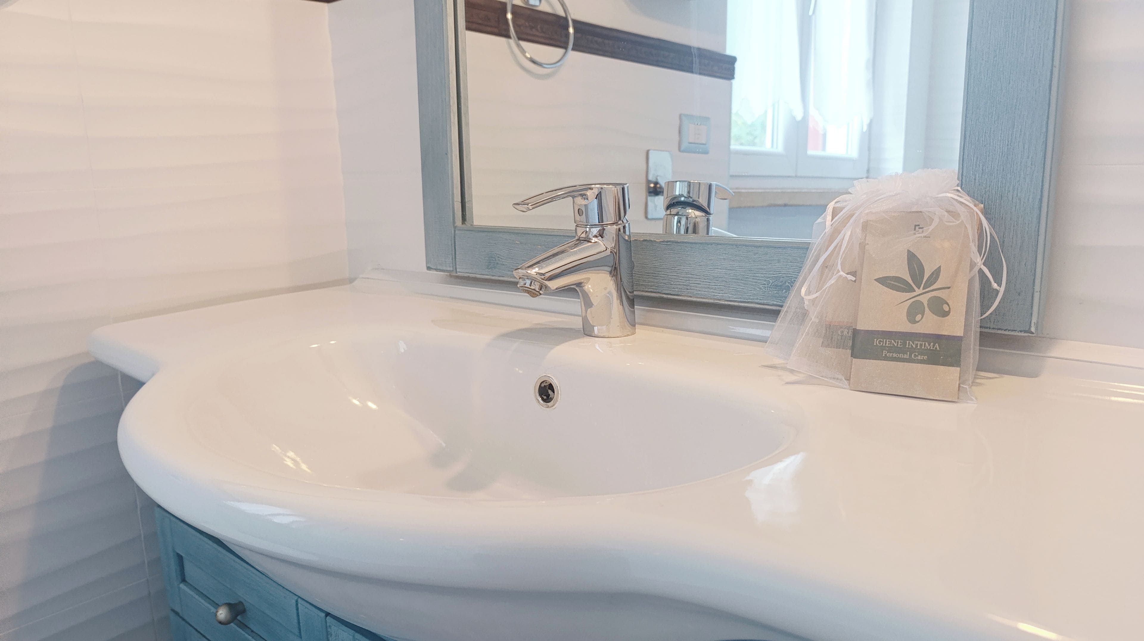A bathroom with a white sink, chrome faucet, and a mirror above it.