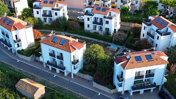 A residential area with modern white buildings, solar panels on rooftops, and a well-maintained road.