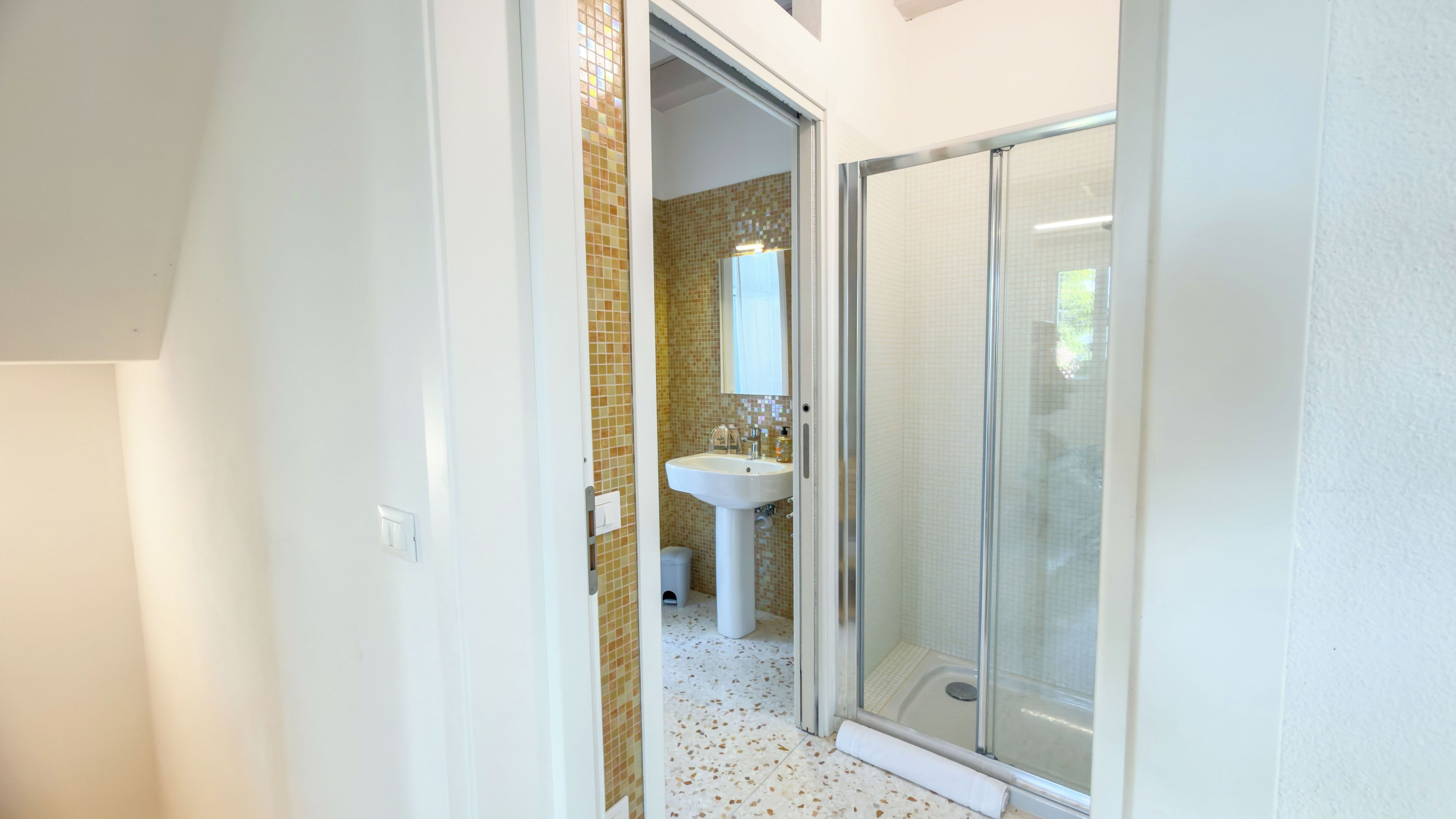 A bathroom with a shower, sink, and tiled walls.
