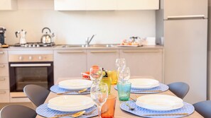 A modern kitchen with a dining table set for four, featuring blue placemats, clear glassware, and a variety of dishes.