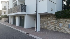 Un edificio residencial moderno con un balcón, una pared de ladrillo y una acera pavimentada.