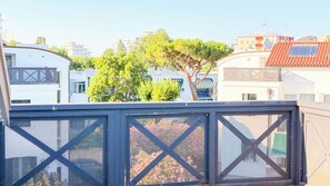 Zona residencial con edificios modernos, un árbol y una valla metálica.