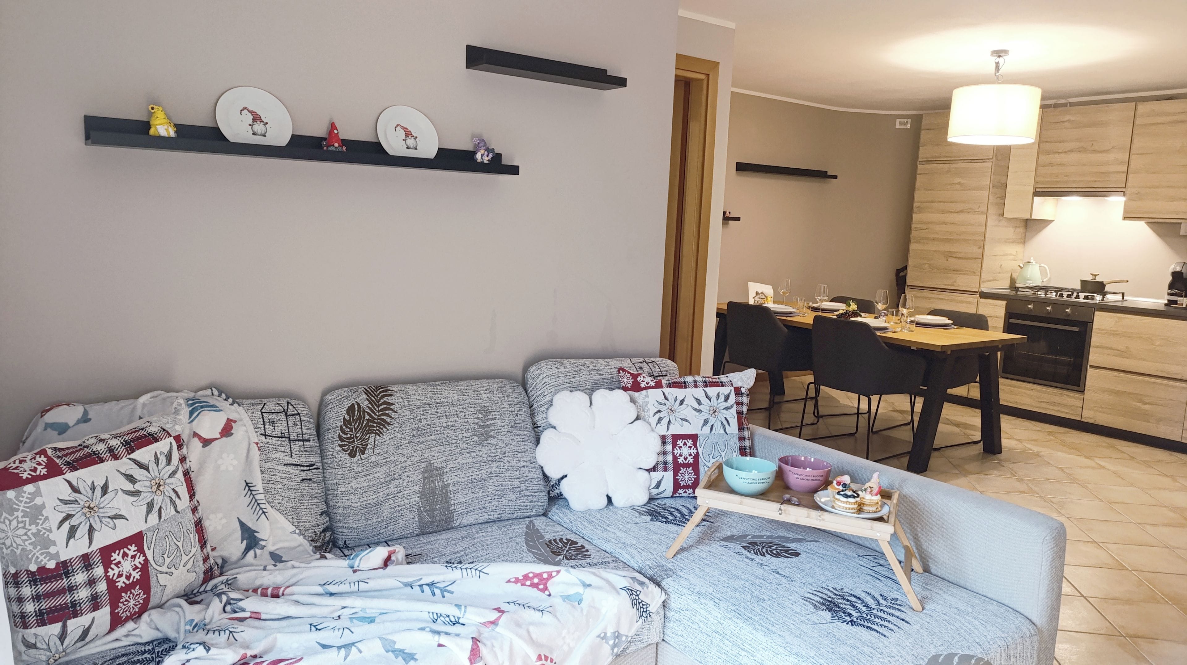 A living room with a sofa, a dining table, and a kitchen area with a stove and cabinets.