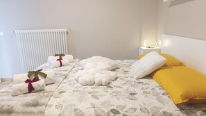 A neatly made bed with a leaf-patterned duvet, white fluffy pillows, and a yellow accent pillow. - La Casa di Fede By Ca-sa Check (Aprica)