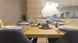 Une table à manger dressée avec des assiettes, des verres et une variété de fruits.