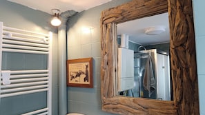 Ein Badezimmer mit einem spiegelnden Holzbettrahmen, einem Handtuchhalter, einem gerahmten Bild und einem weißen Heizkörper.