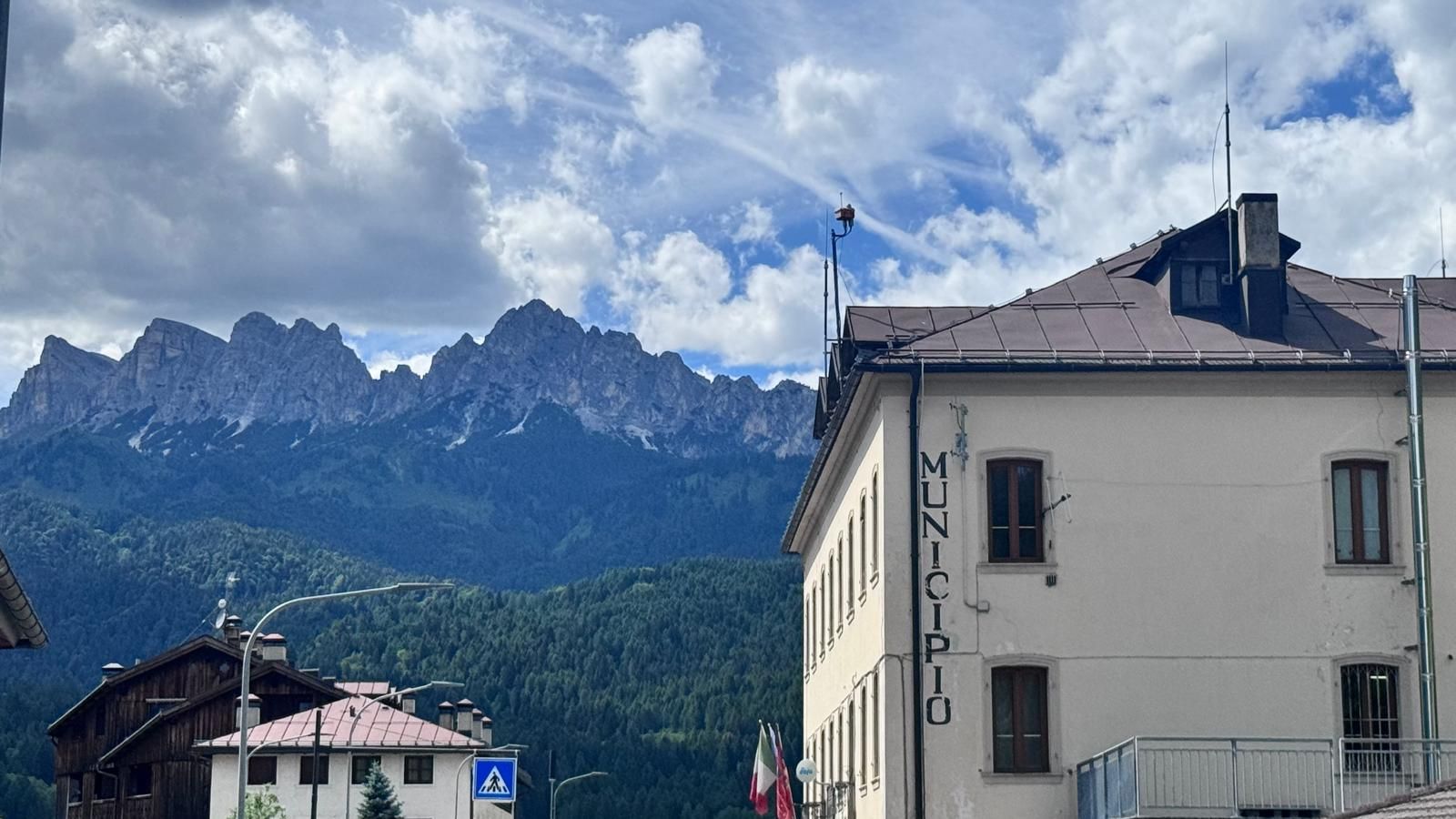 A building with 'MUNICIPIO' signage, surrounded by mountains and a partly cloudy sky.