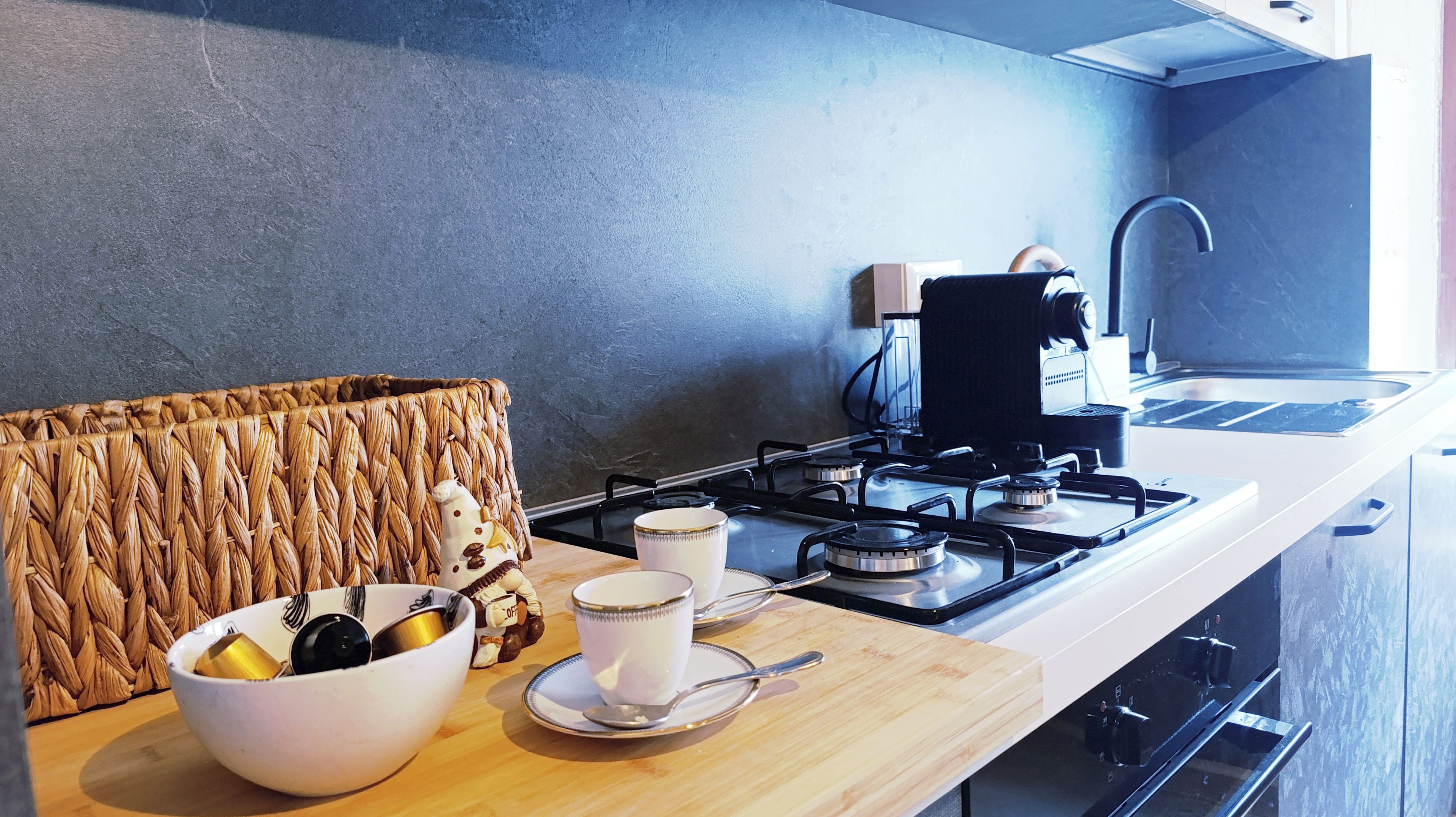 A modern kitchen with a gas stove, a coffee maker, and a woven basket on the counter.