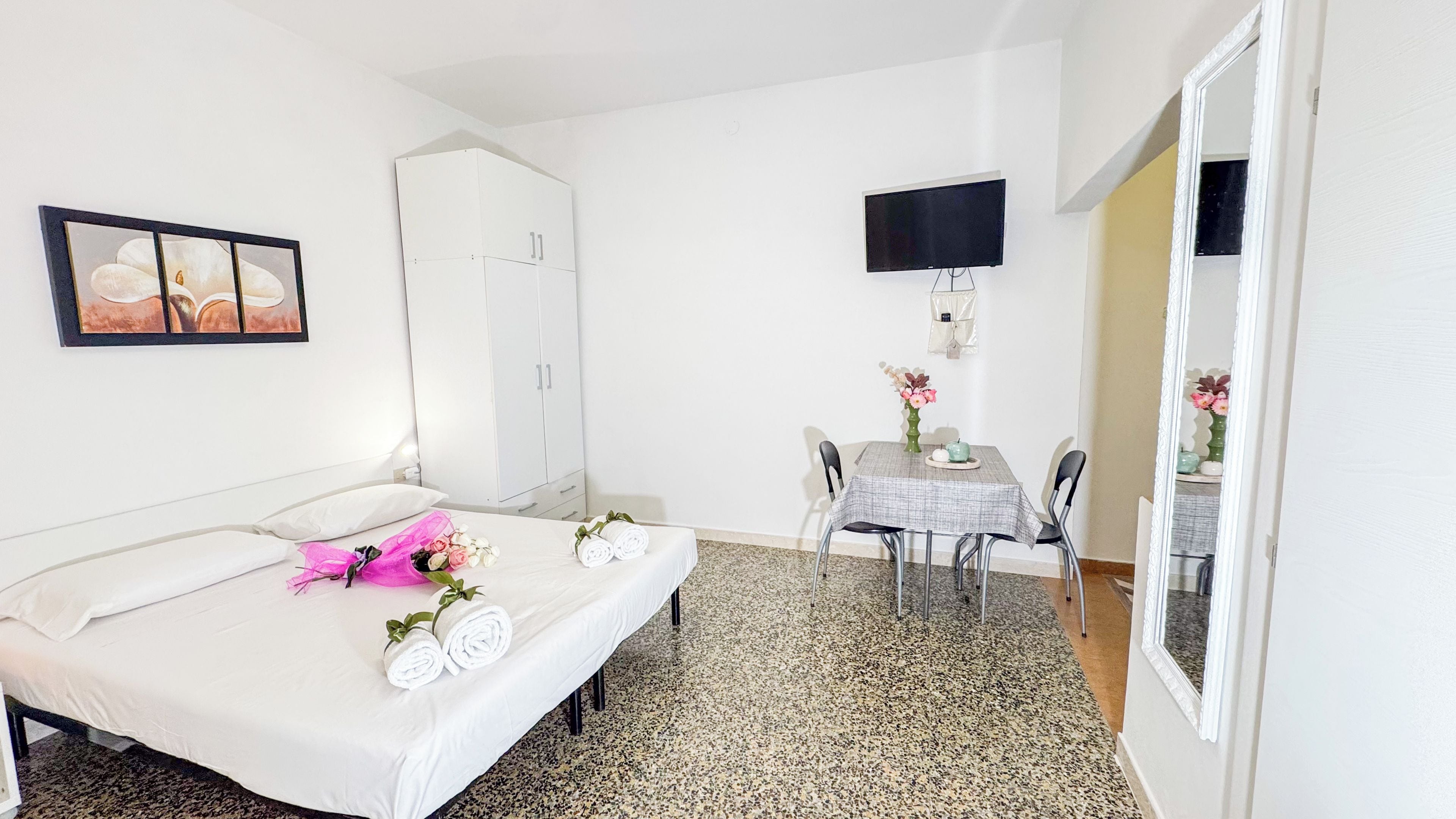 A hotel room with a bed, a desk, a chair, a television, and a wardrobe.