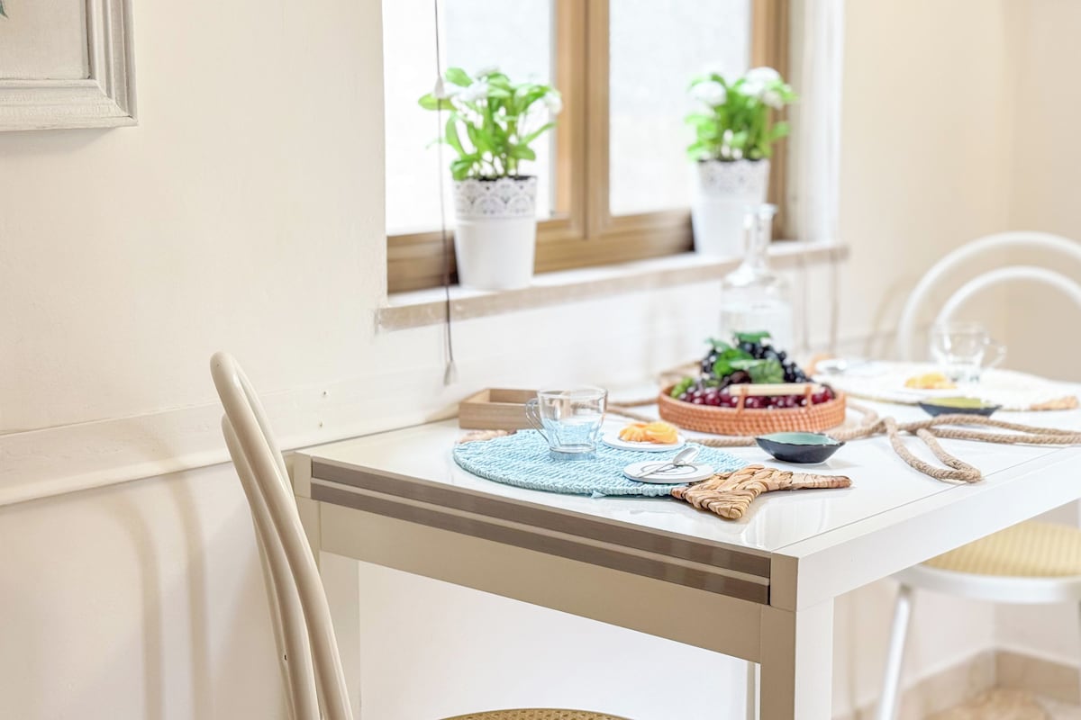 A dining table with a placemat, a glass, and a bowl of fruit.