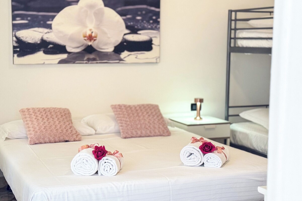 A hotel room with a bed, two pillows, a nightstand, a lamp, and a framed picture on the wall.