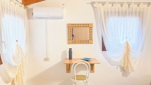 A room with a wooden table, a white chair, a wall-mounted air conditioner, and two windows with sheer curtains. - Cà 4 nevodi Chiara by Ca-Sa Check (Chioggia)