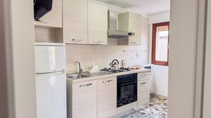 Eine kleine Küche mit Kühlschrank, Herd, Spüle und Backofen.