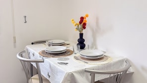 Ein Esstisch ist gedeckt mit Tellern, einer Blumenvase und einem an der Wand montierten Lichtschalter.