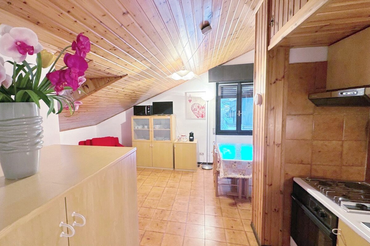 A kitchen with wooden cabinets, a stove, and a dining area with a table and chairs.