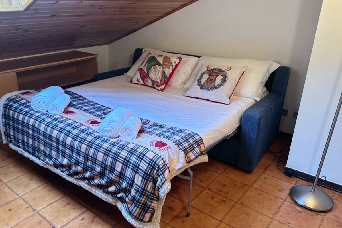 A bedroom with a bed, a bench, and a floor lamp.