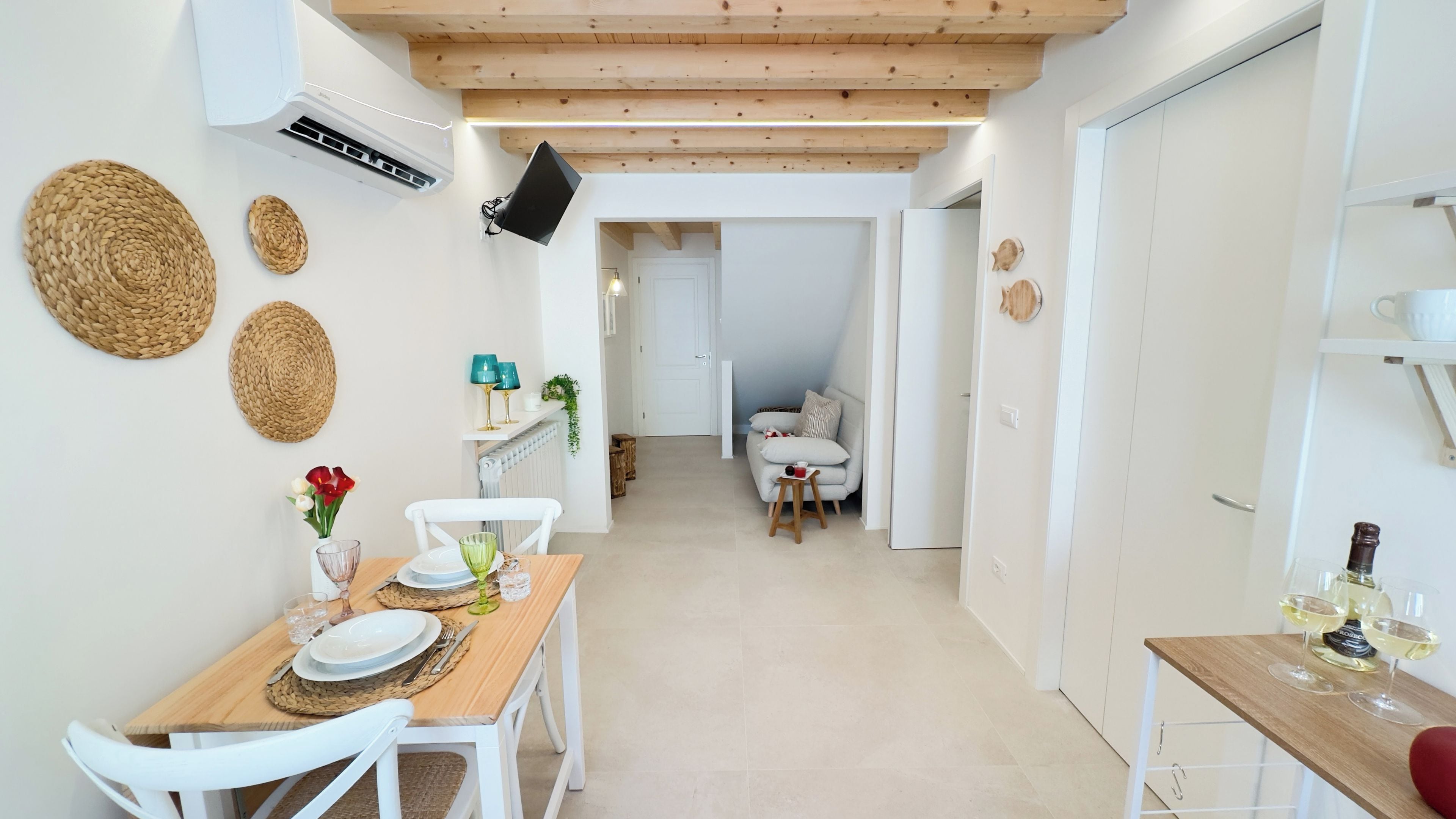 A dining area with a wooden table, white chairs, and woven placemats.