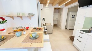 Eine moderne Küche mit weißen Schränken, einer Holzarbeitsplatte und einem Essbereich mit Tisch für zwei Personen.