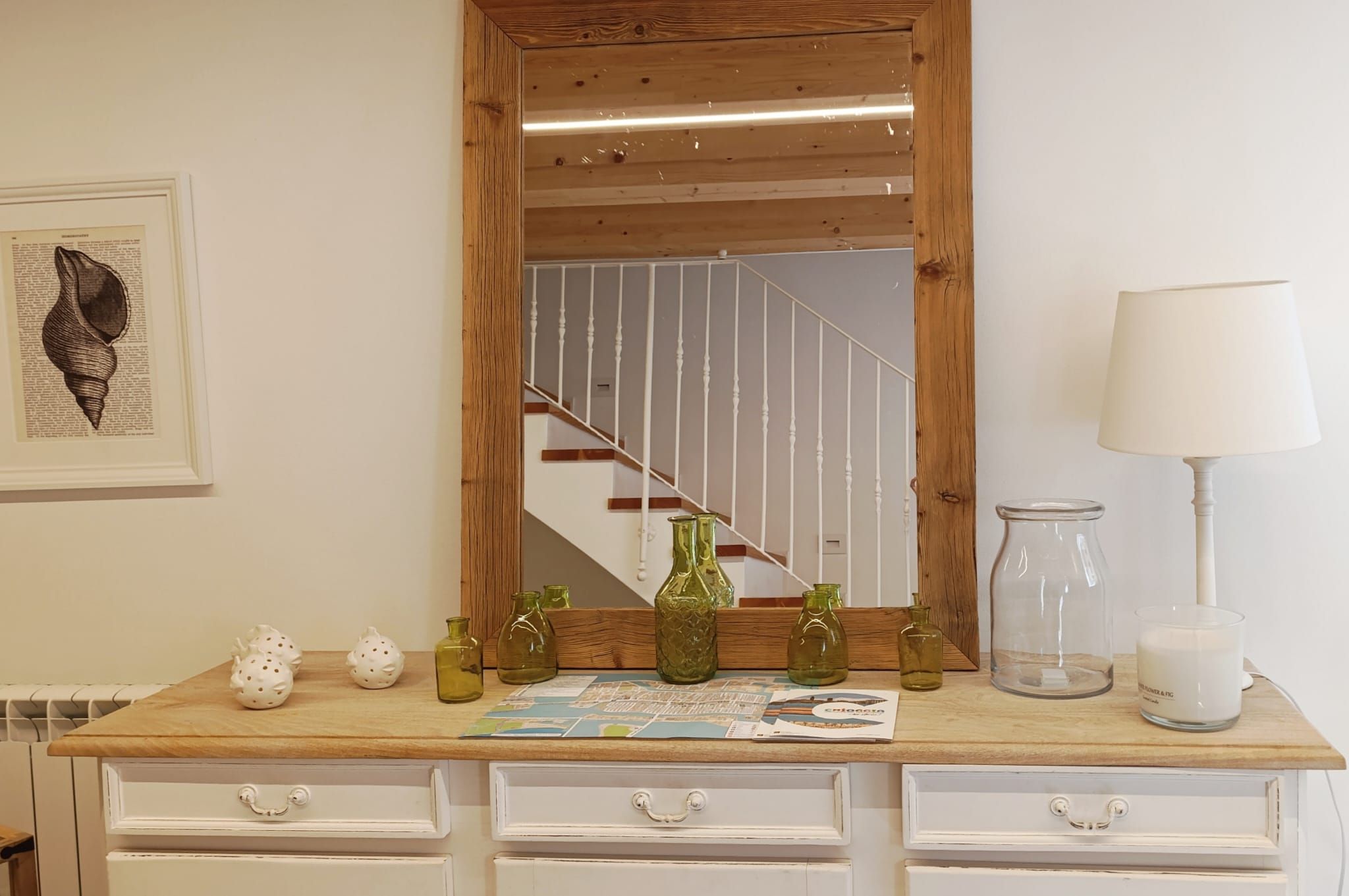 A wooden dresser with a mirror, decorative vases, and a candle.