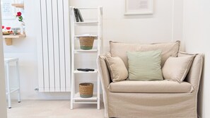 Ein beiges Sofa mit gestreiften Kissen, eine weiße Regaleinheit mit Körben und ein gerahmtes Zitat an der Wand.