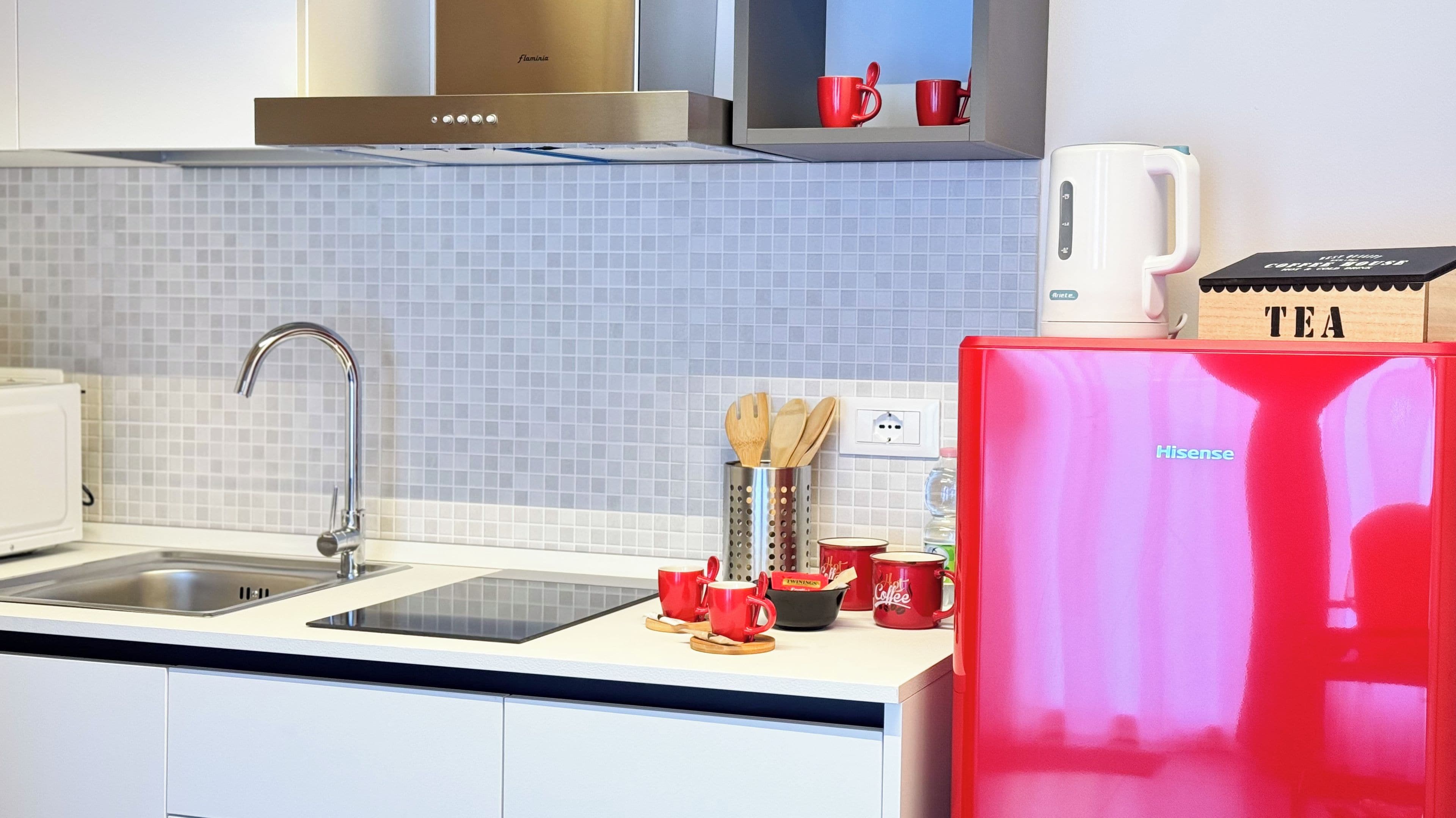 Una cucina moderna con un frigorifero rosso, una macchina per il caffè e un bollitore.