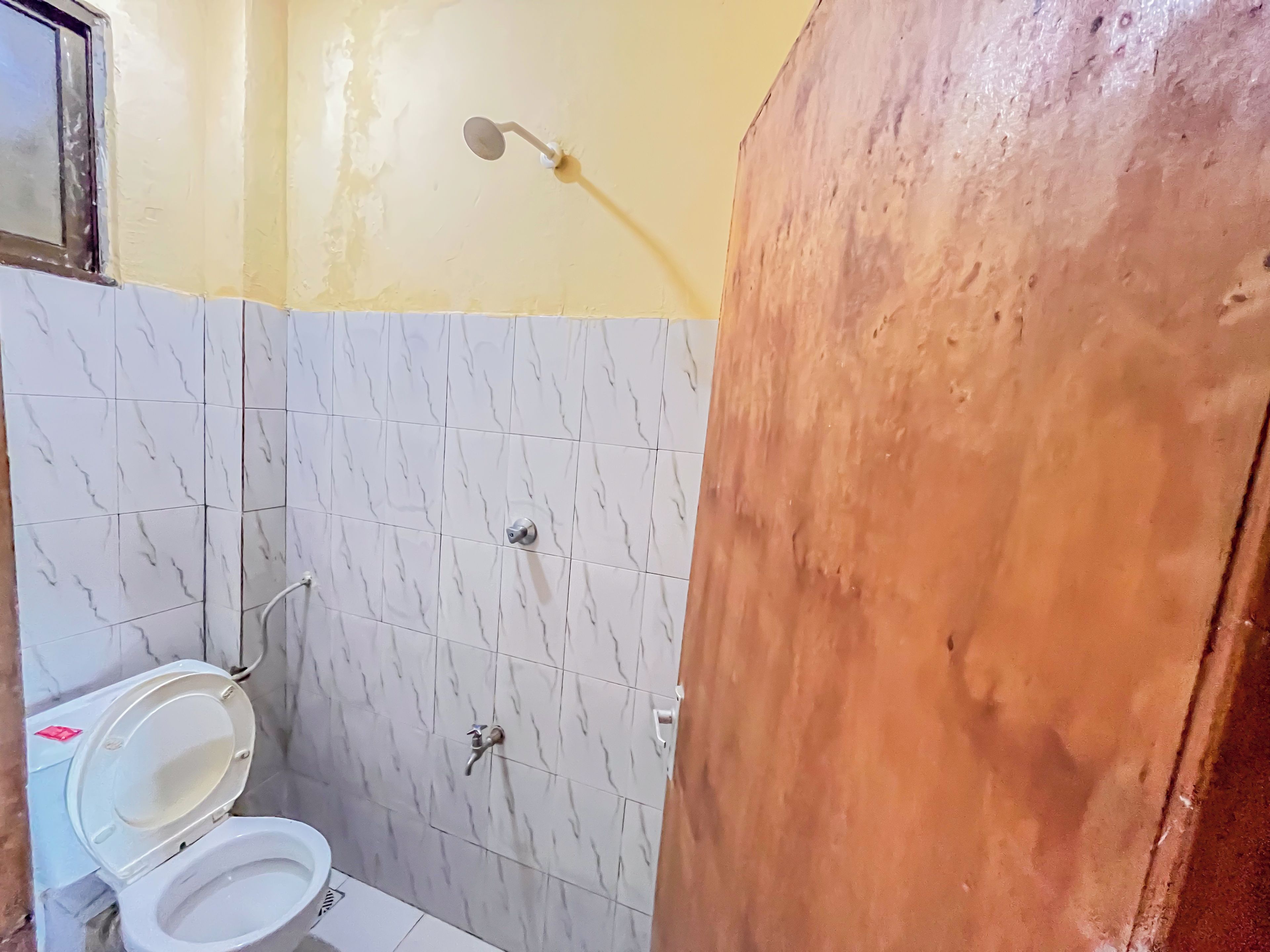 Casa de banho com sanita, chuveiro e lavatório.