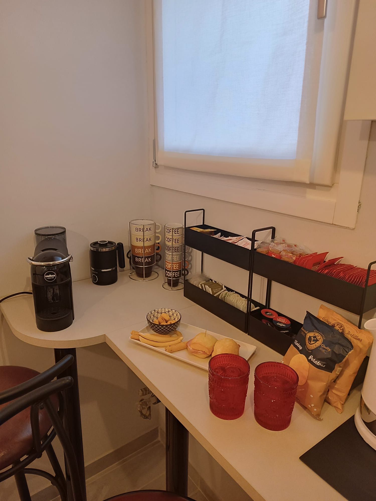 A breakfast bar with coffee makers, a bread basket, and a snack shelf.