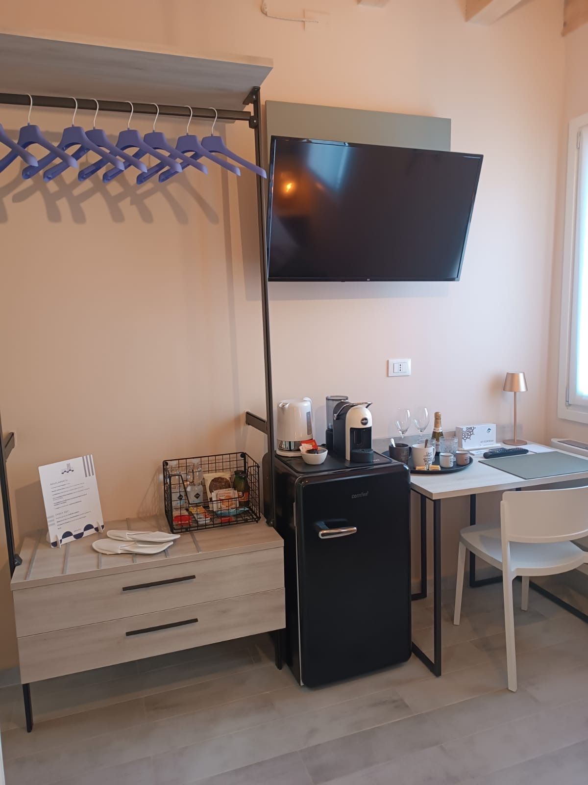 Une petite cuisine équipée d’un réfrigérateur, d’une machine à café et d’une petite table à manger avec une chaise.