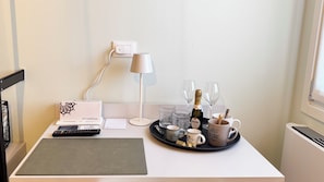 A neatly arranged workspace with a desk, a keyboard, a lamp, a tray with coffee mugs, glasses, and a bottle of champagne. - Do Campanili by Ca-sa Check (Chioggia)