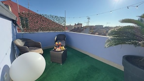 A rooftop terrace with green artificial turf, wicker furniture, and a table with balloons and snacks. - Do Campanili by Ca-sa Check (Chioggia)
