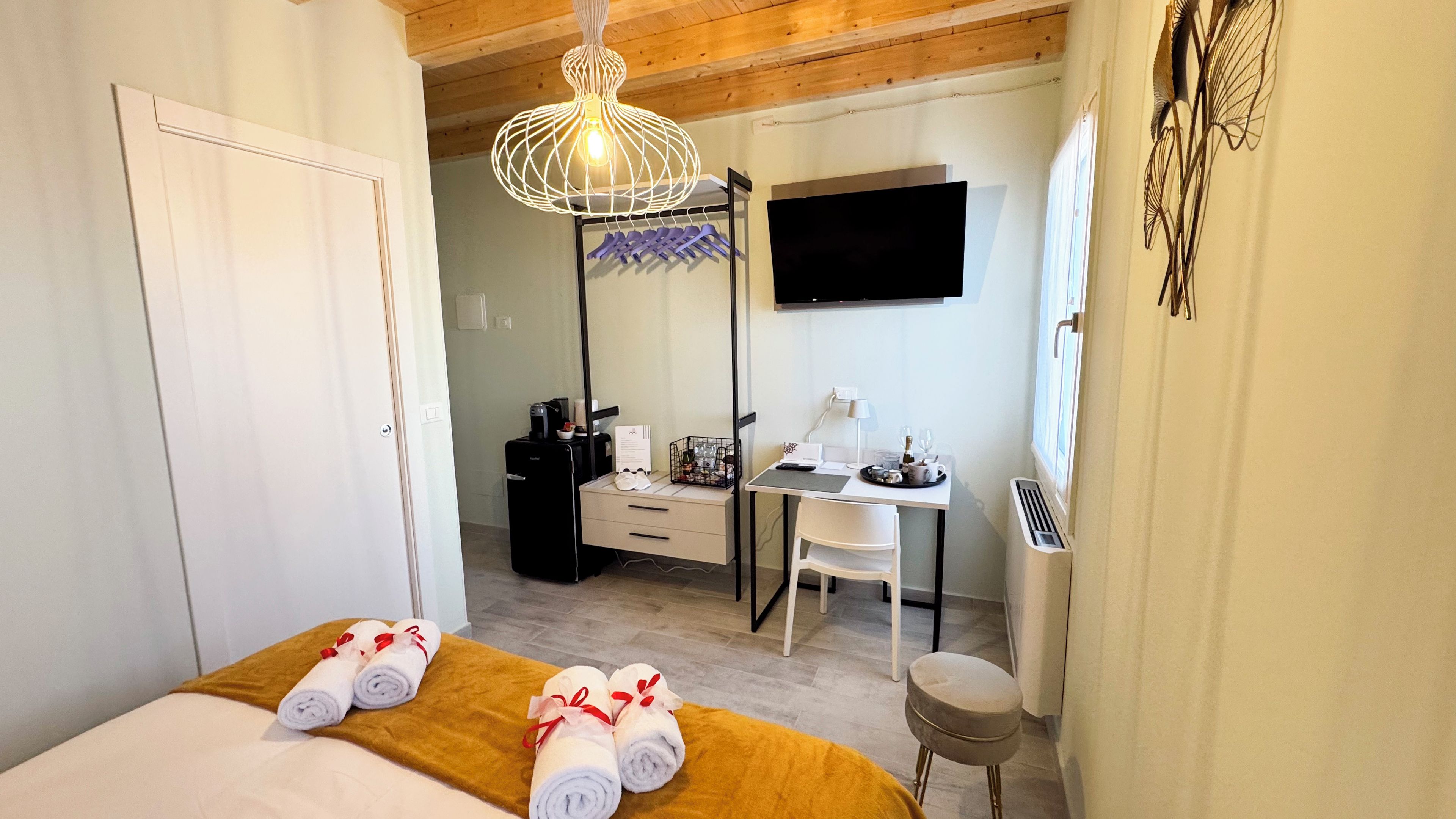 Une chambre d’hôtel avec un lit, un bureau, une chaise, une télévision et une fenêtre.
