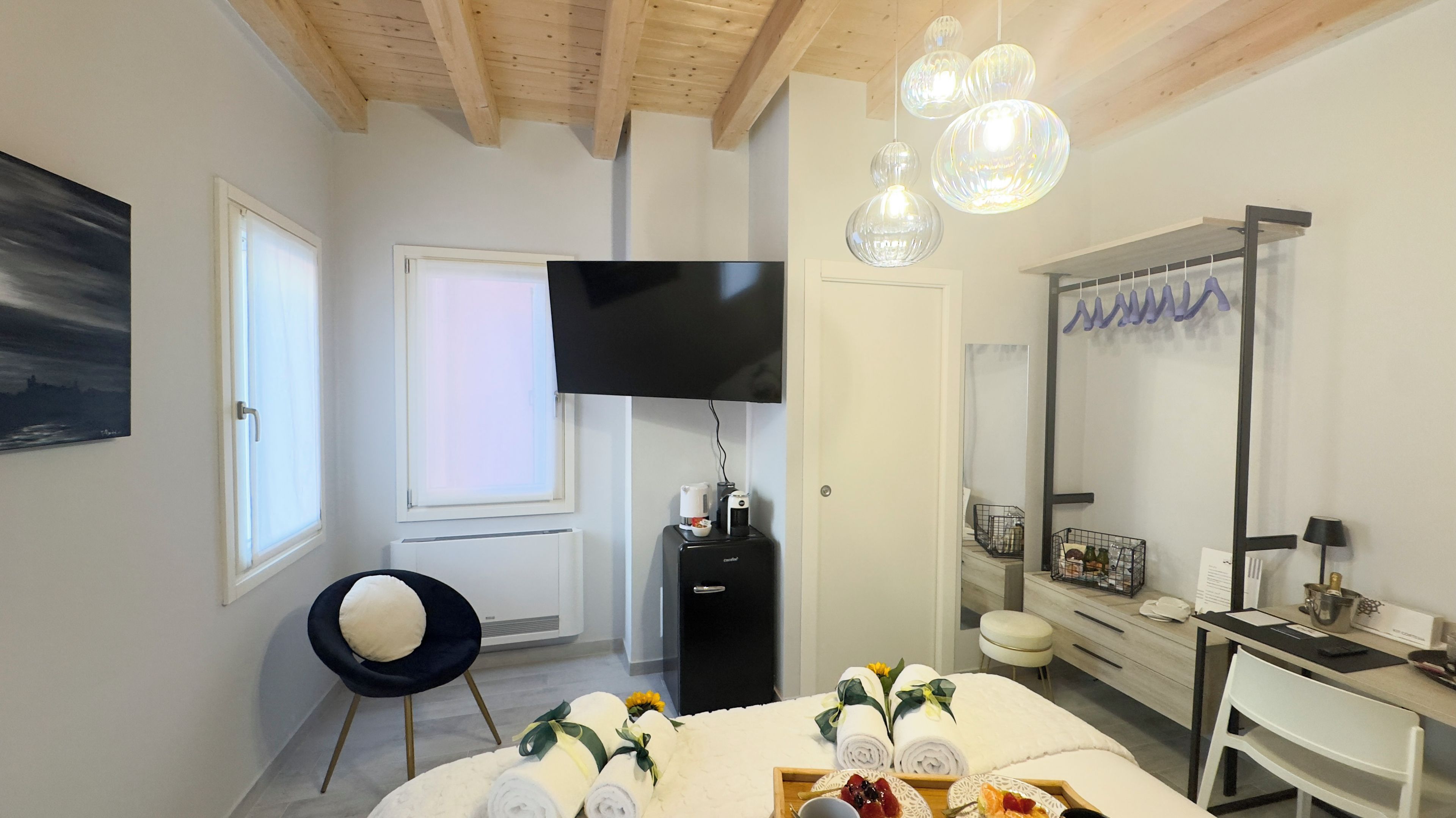 Een moderne hotelkamer met een groot bed, een zithoek met een fauteuil, een televisie en een spiegel.