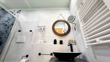 Une salle de bain moderne avec un lavabo noir, un miroir rond, un sèche-cheveux et un porte-serviettes.