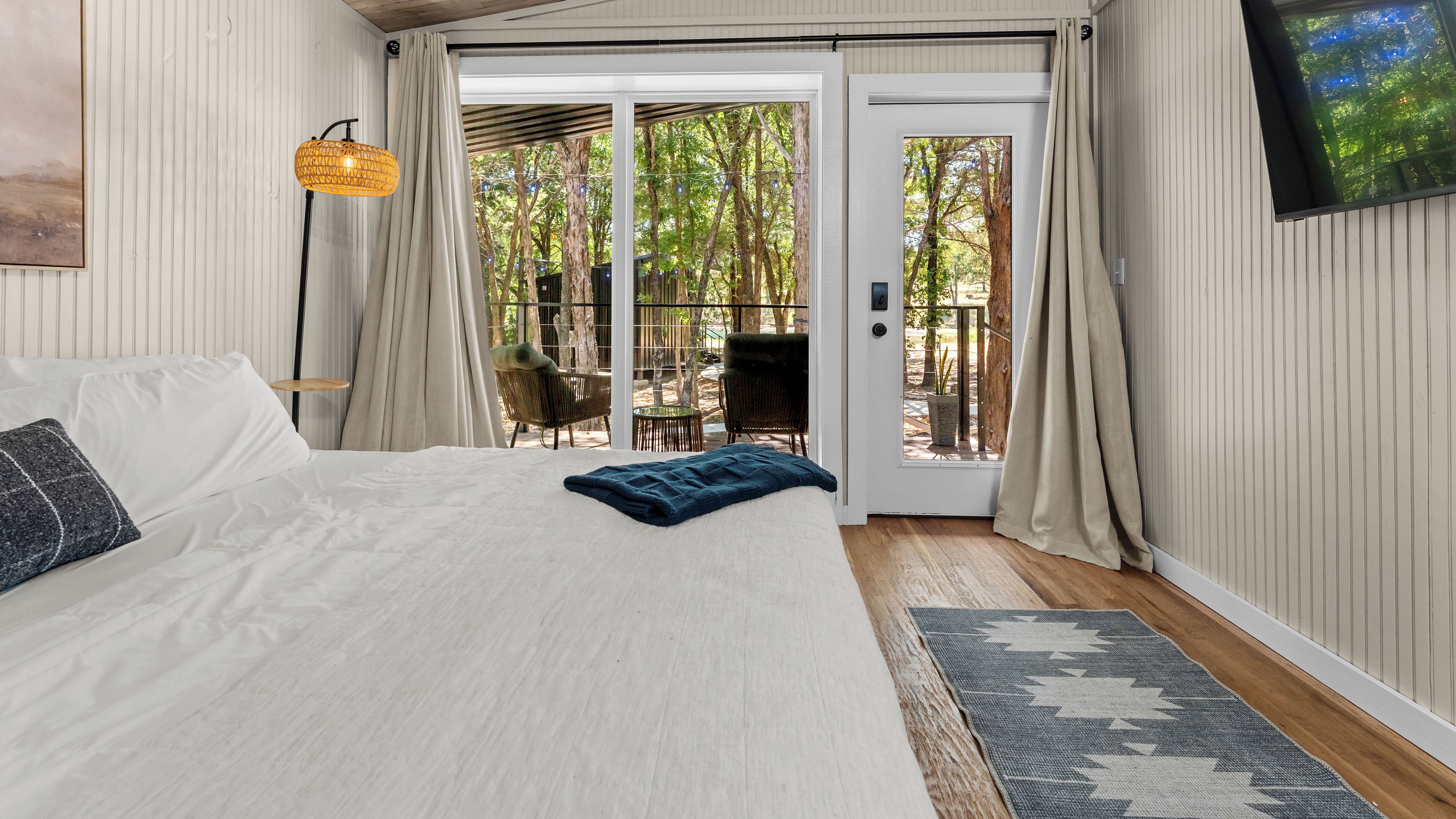 A bedroom with a bed, a window, a door, and a view of the outdoors.