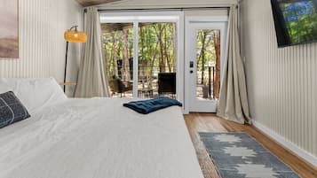 A bedroom with a bed, a window, a door, and a view of the outdoors.
