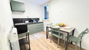 Una cocina compacta con zona de comedor, equipada con electrodomésticos básicos y una ventana que proporciona luz natural.