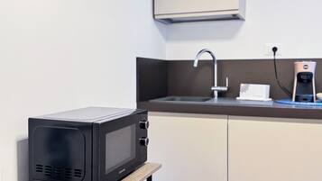 Une petite cuisine équipée d’un four à micro-ondes, d’une machine à café et d’un évier.