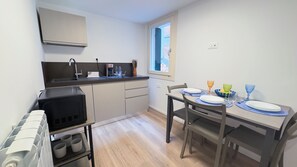Cocina compacta con horno integrado, cafetera y ventana sobre el lavabo.
