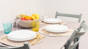 A dining table set with white plates, gold cutlery, and a bowl of fruit. - Tre Esse by Ca-sa Check (Chioggia)