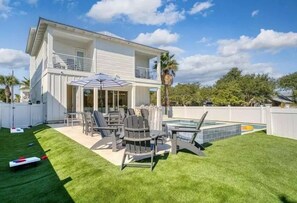 Et toetagers hus med en terrasse, udendørs møbler og en swimmingpool.